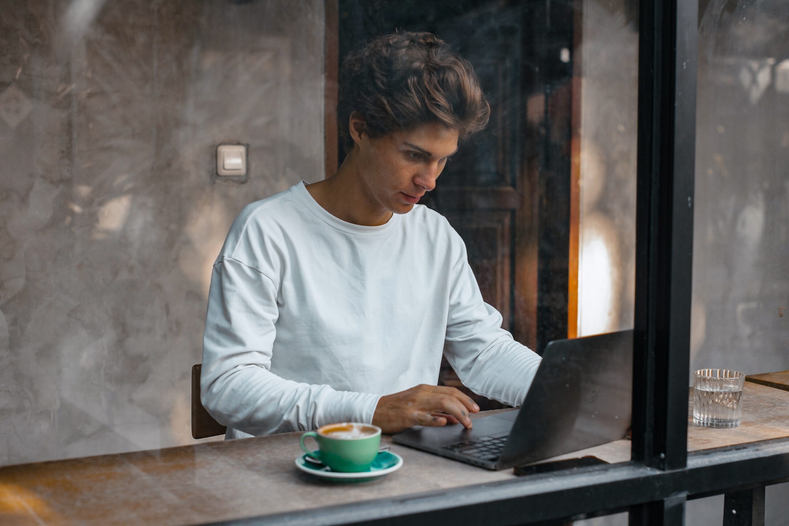 En man som sitter på ett café och jobbar med sin dator